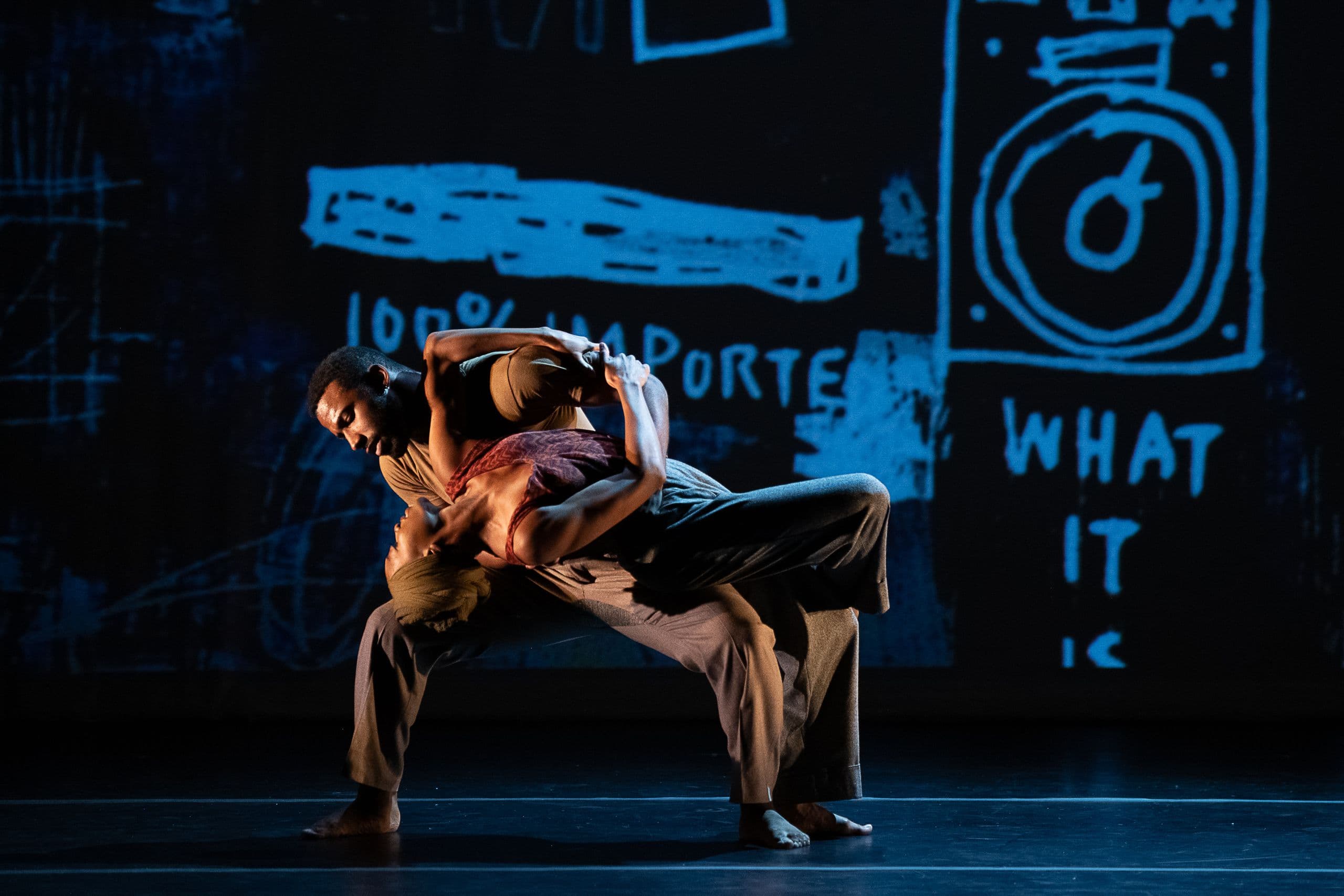 Two dancers in a dip against a projected chalkboard-style backdrop.