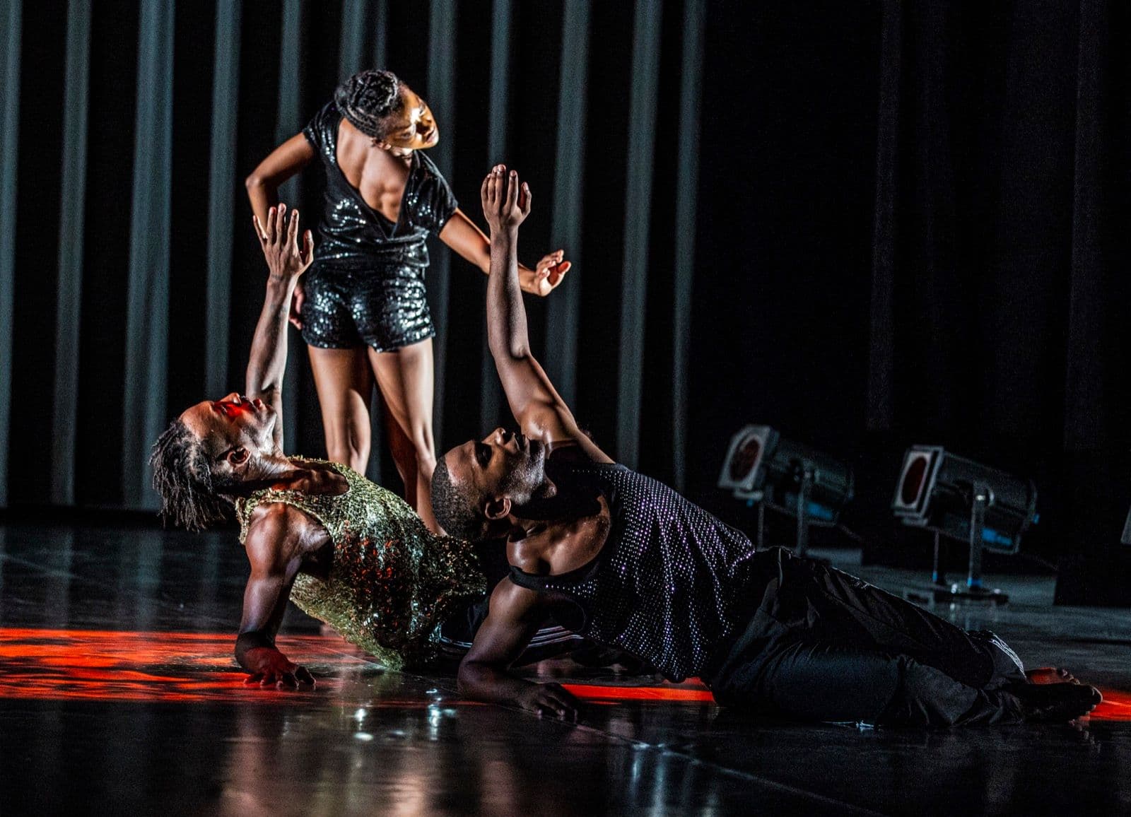 Tamisha Guy stands over Jae Neal and Claude CJ Johnson during a group scene.