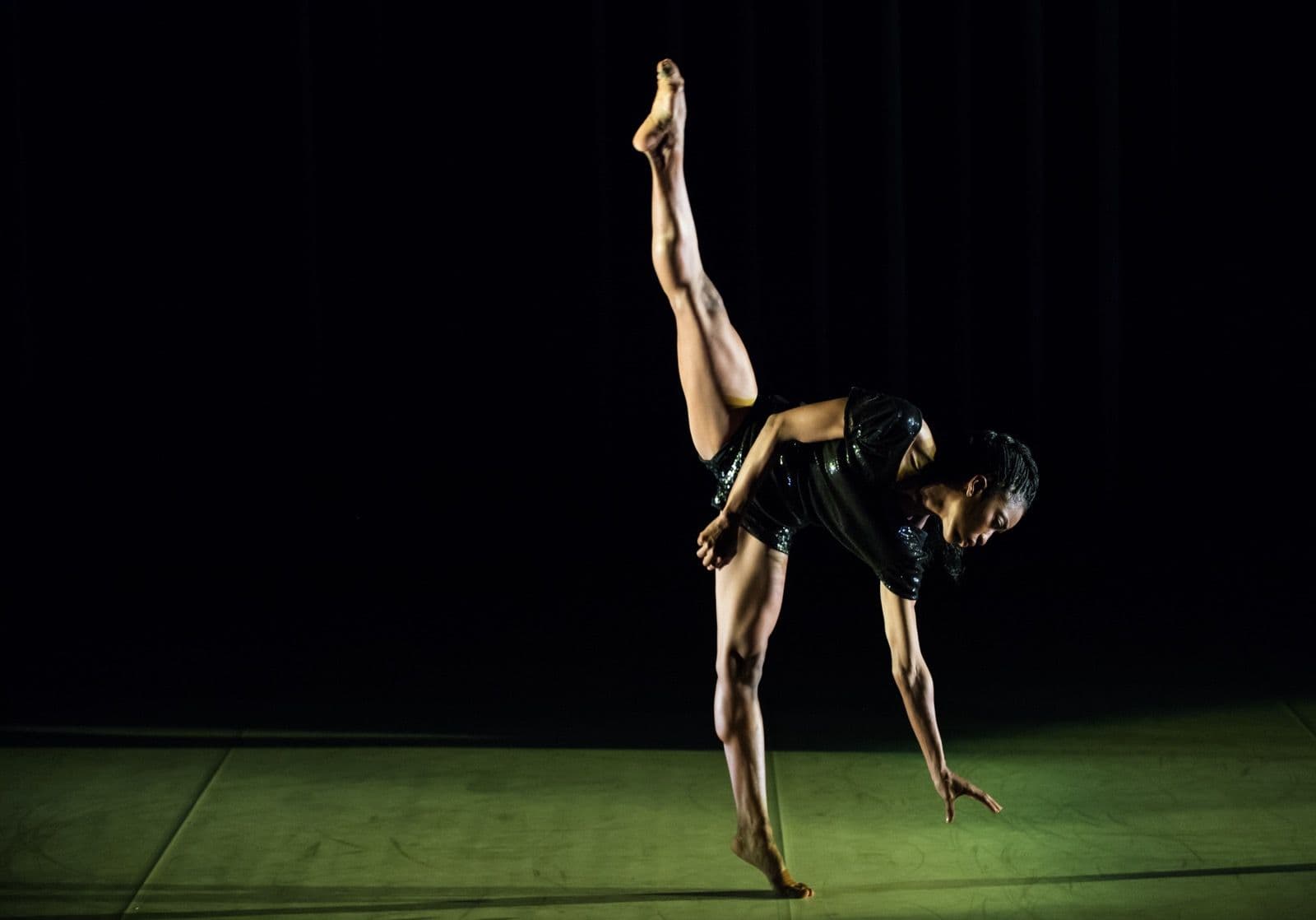 Tamisha Guy performs a one-handed balance with one leg extended upward.