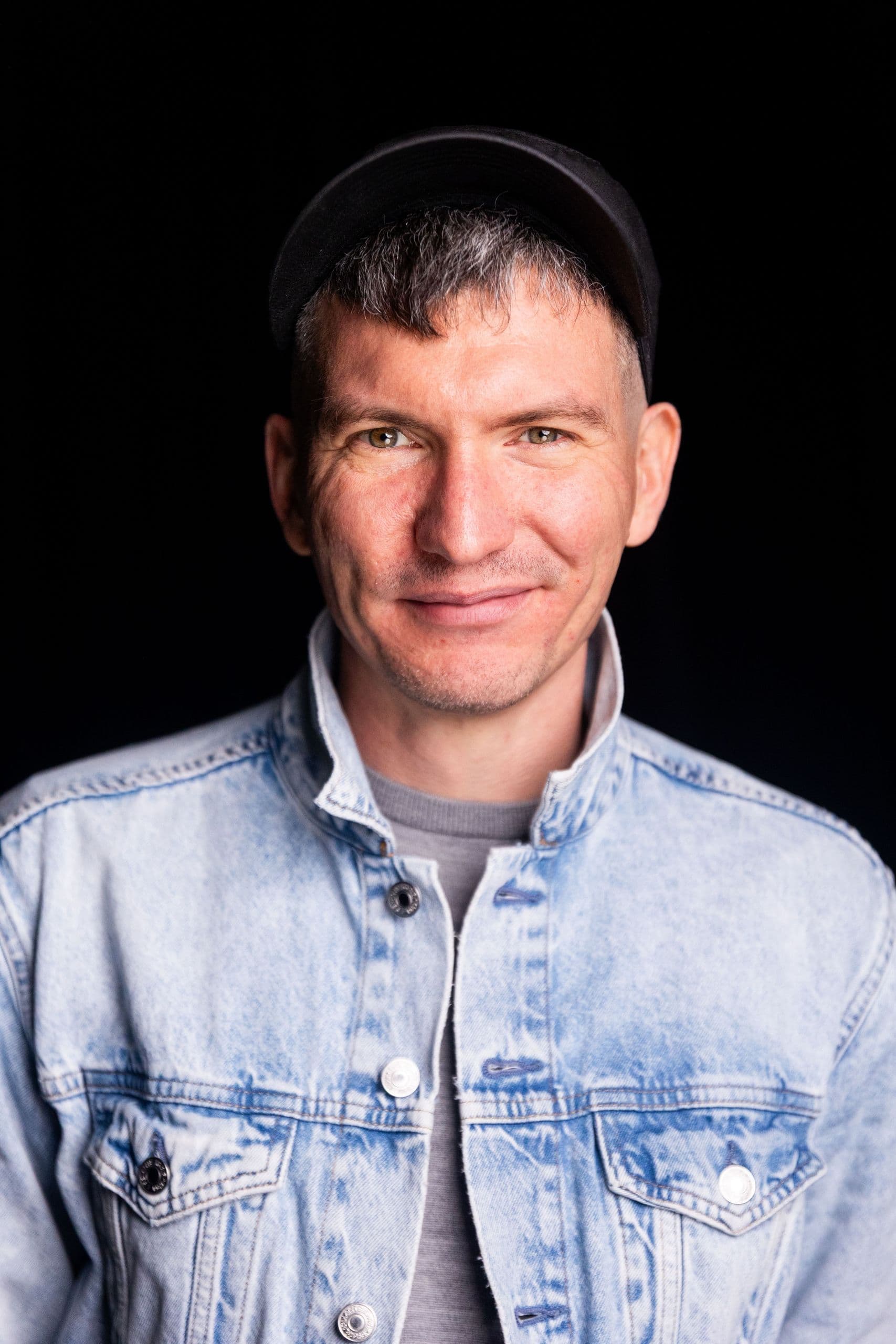 Ben Pryor stands in front of a black back drop for a portrait.