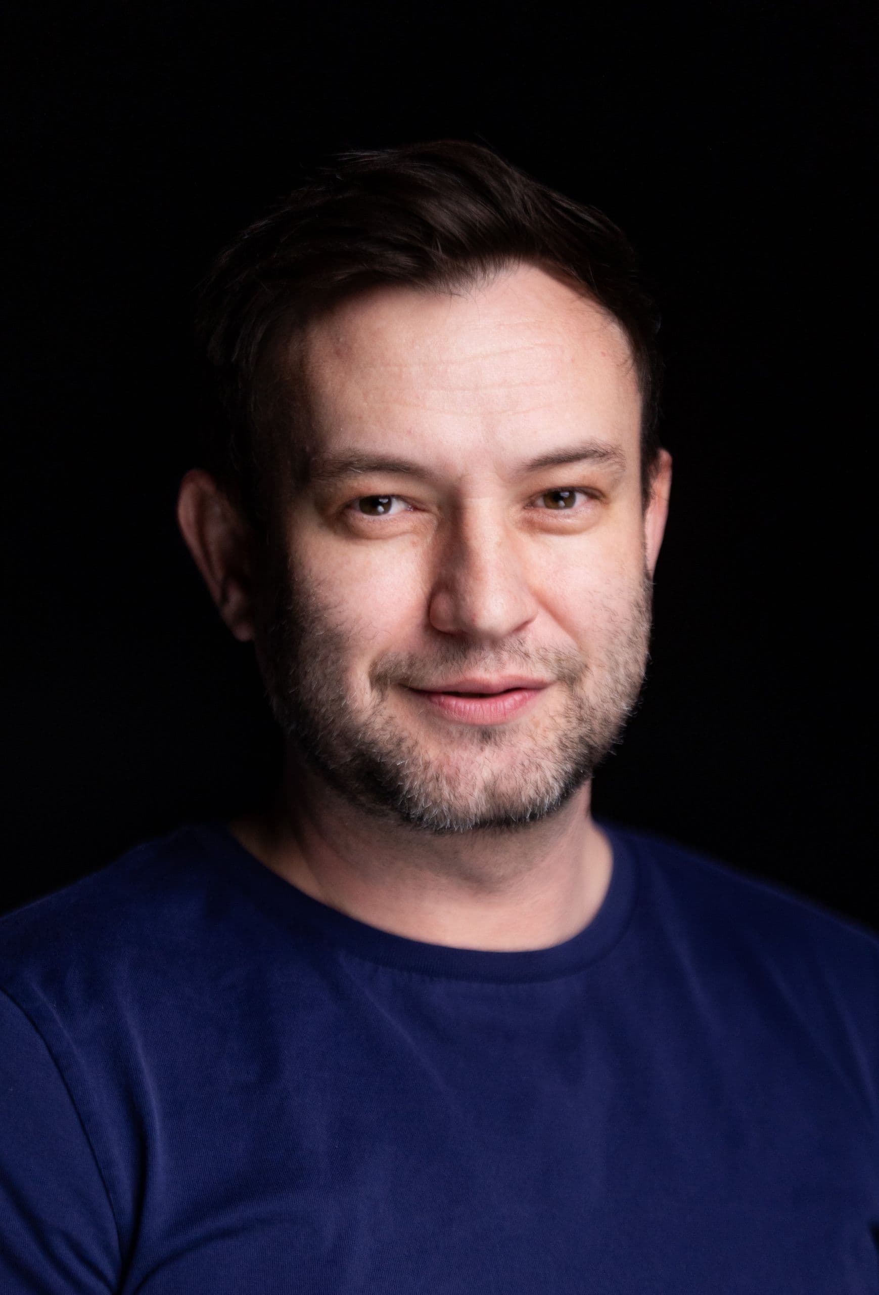 Matthew Baker stands in front of a black backdrop for a portrait.